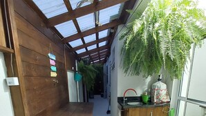 A narrow corridor with a wooden bench, a sink with a green mat, and a potted plant. - APARTMENT FREE FOR NEW YEAR'S EVE. (Ingleses Sul Florianópolis)