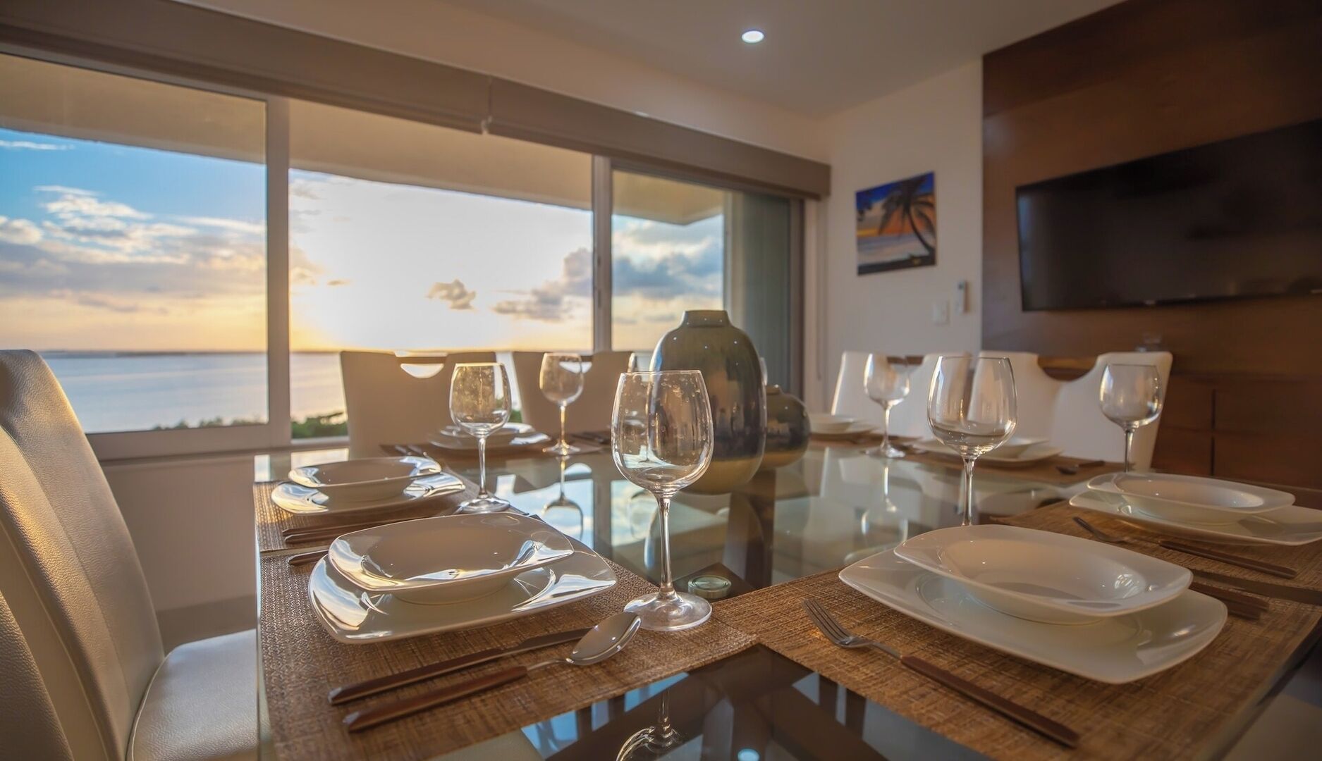 A dining table set with plates, glasses, and cutlery, overlooking a scenic view.