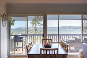 Enjoy ocean views from the dining area, featuring a large table and chairs, and access to a patio with seating and a barbecue grill.