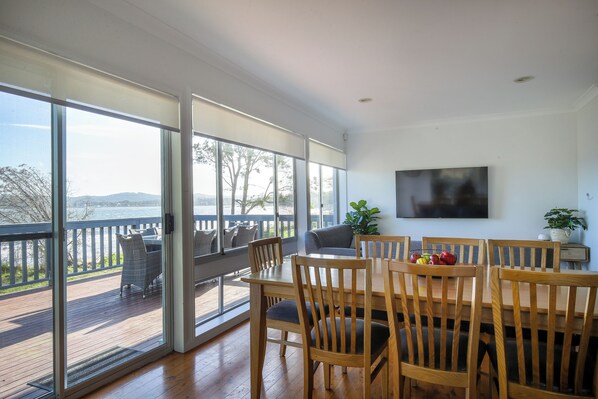Un comedor con vistas al exterior, muebles de madera y un televisor de pantalla plana en la pared.