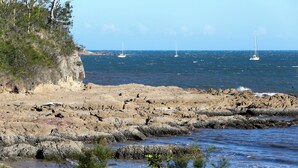 Eine felsige Küstenlinie mit freiem Blick auf das Meer und Segelboote.
