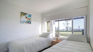 Ein Schlafzimmer mit zwei Betten, einem Fenster mit Blick ins Freie und einem Gemälde an der Wand.