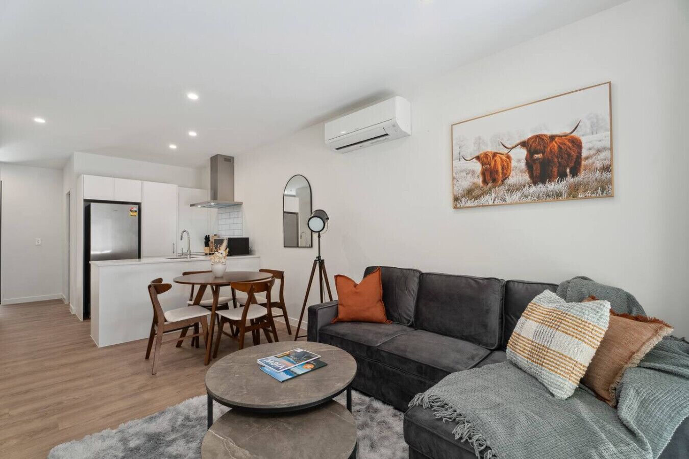 A modern apartment with a living room, dining area, and kitchen.