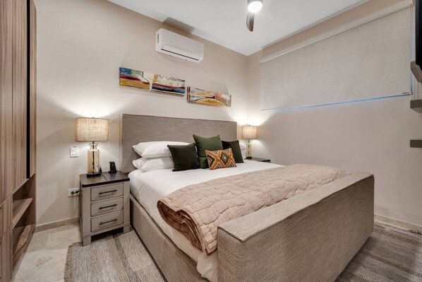 A bedroom with a large bed, bedside tables, an air conditioning unit, and artwork on the wall. - 2 Pools, Jacuzzi, Close to Beaches, Rooftop, Cozy (Cabo San Lucas)