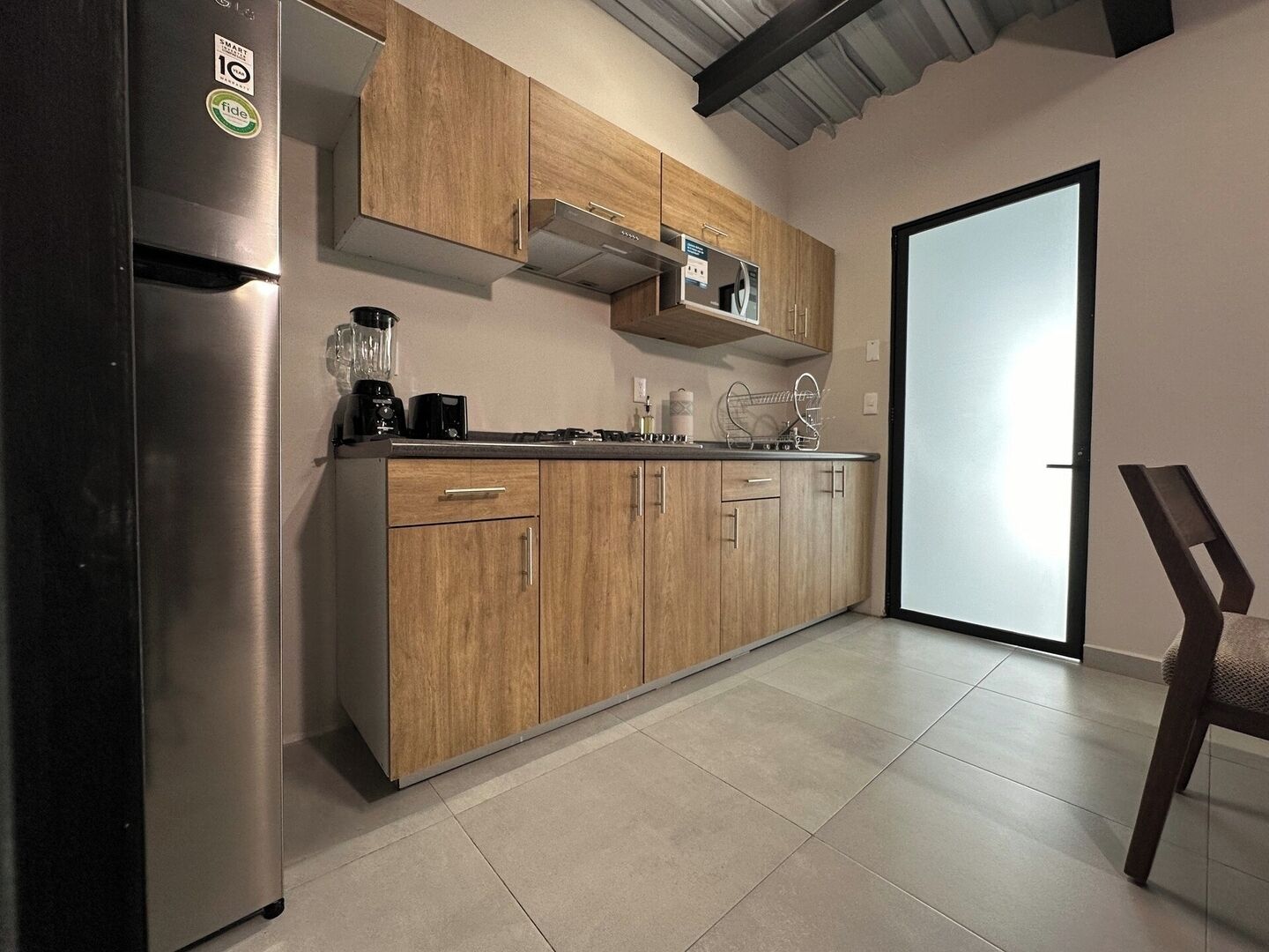 A modern kitchen with wooden cabinets, a stainless steel refrigerator, and a microwave.