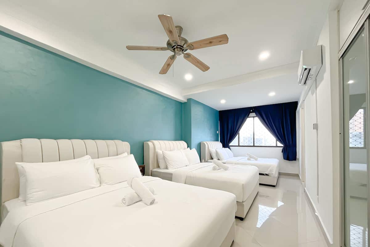 A hotel room with two beds, a ceiling fan, a large window with curtains, and a glass door leading to a balcony.