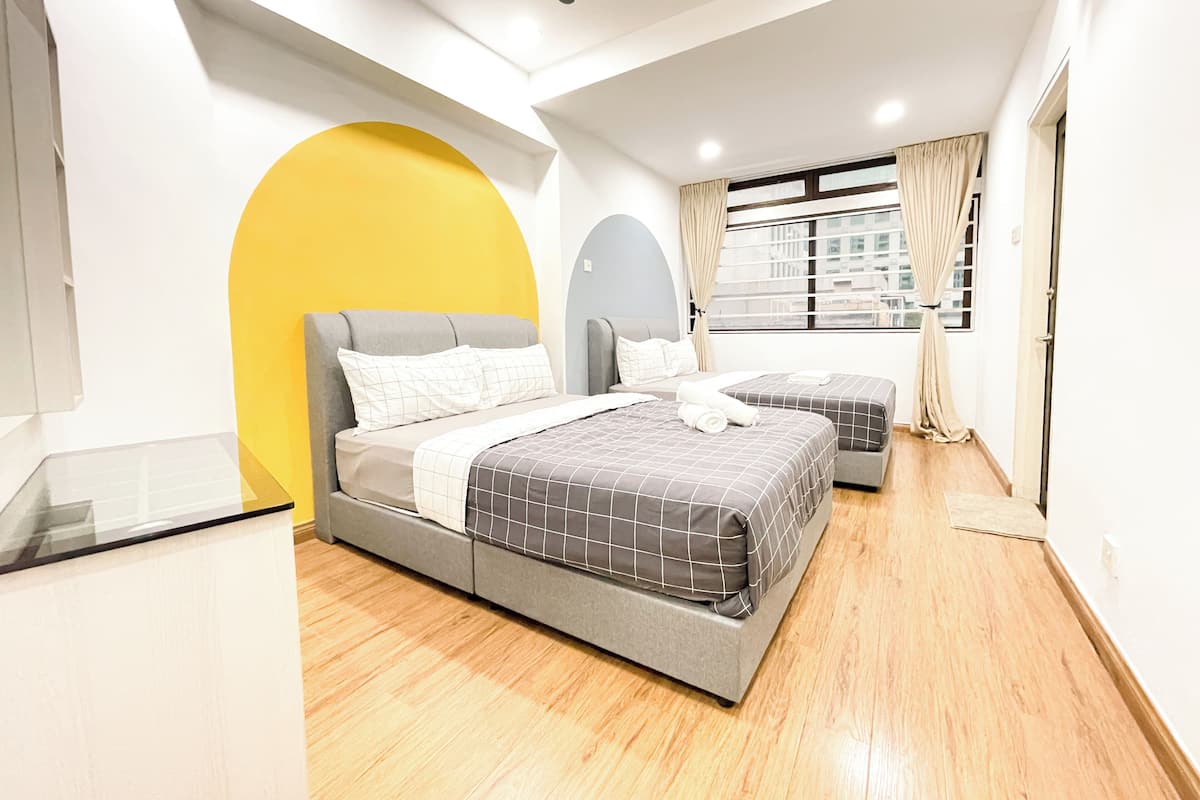 A modern bedroom with a bed, two bedside tables, a window with curtains, and a view of buildings.