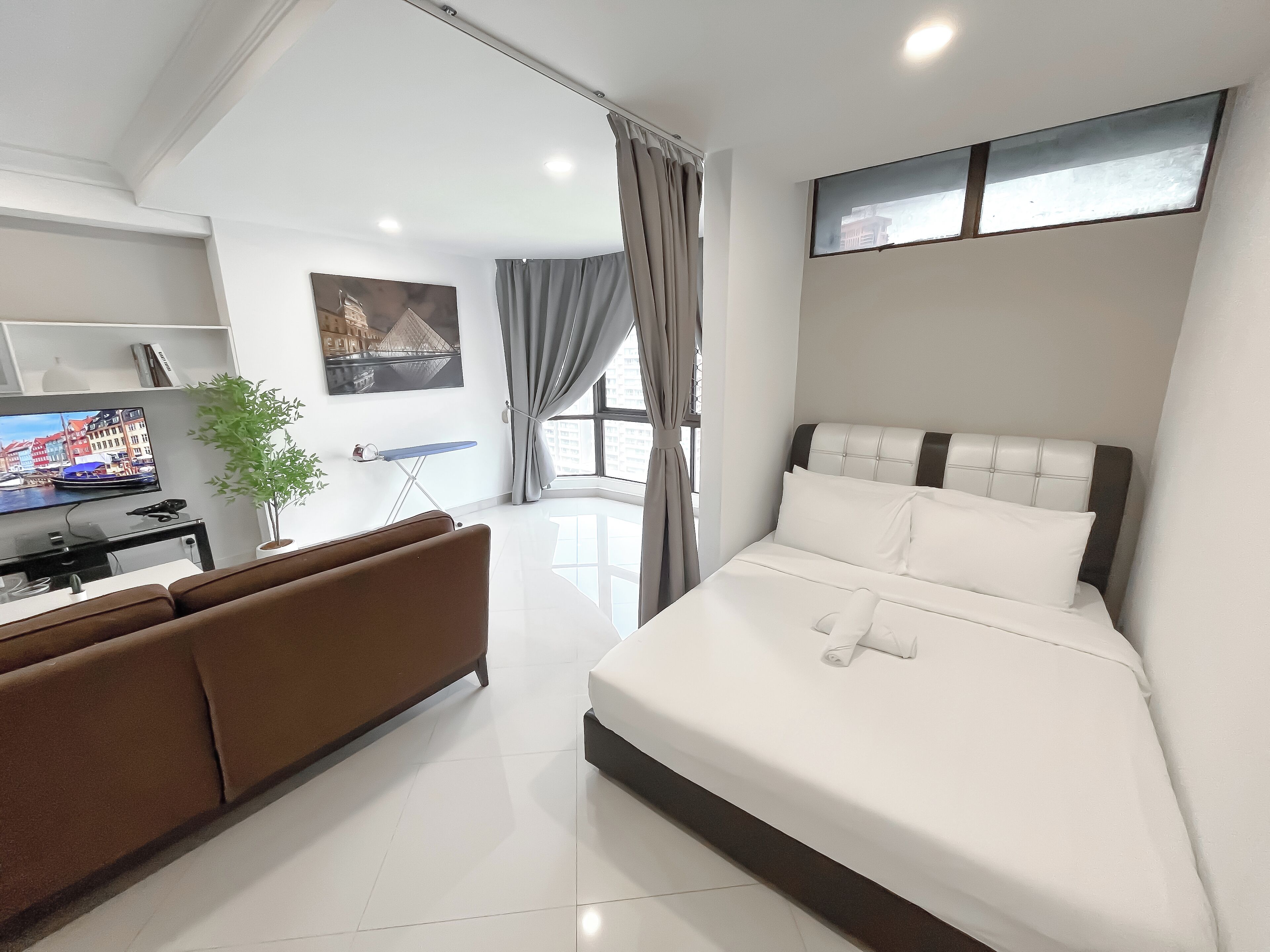 Habitació d'hotel moderna amb un llit, una televisió, una taula de treball i una finestra.