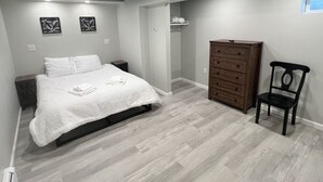 Une chambre à coucher comprenant un lit, une commode, une chaise et un dressing.