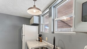 A compact kitchen with a white refrigerator, double sink, and a hanging pendant light. - Affordable, Private, Single Level House Steps From Hard Rock Casino Pet Friendly (Bristol)