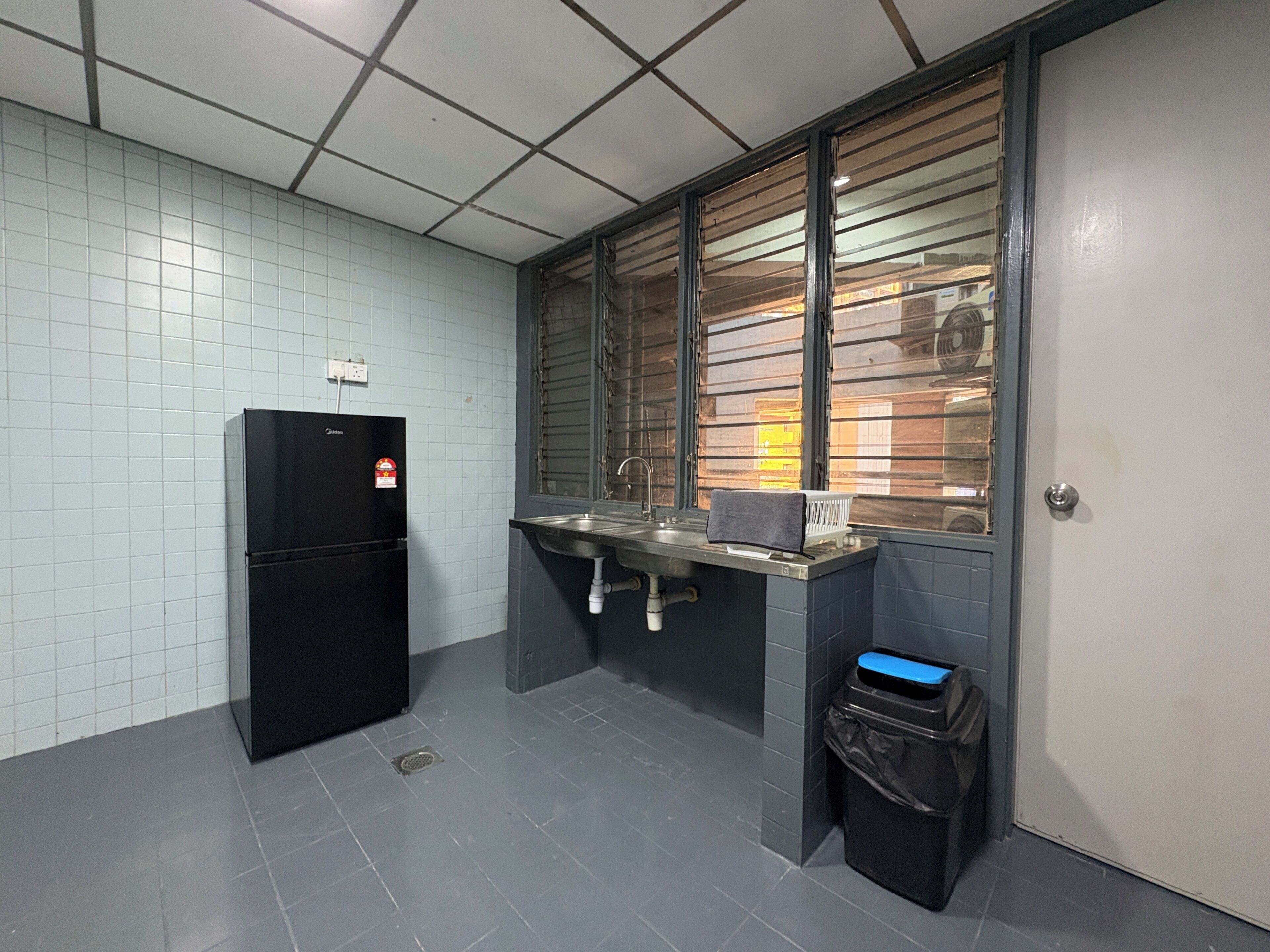 Eine kleine Küchenzeile mit Kühlschrank, Spüle und Fenster.
