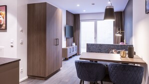 A modern kitchen with wooden cabinets, a dining table with chairs, and a TV mounted above the counter. - Cosy Apartment on the Ski-slope (Hopfgarten im Brixental)