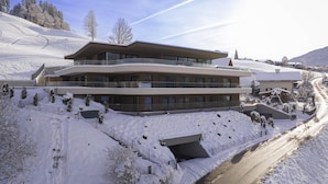 A multi-story building with a ski slope in the background. - Cosy Apartment on the Ski-slope (Hopfgarten im Brixental)