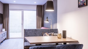 A modern room with a wooden table, a bench, a lamp, and a large window. - Cosy Apartment on the Ski-slope (Hopfgarten im Brixental)