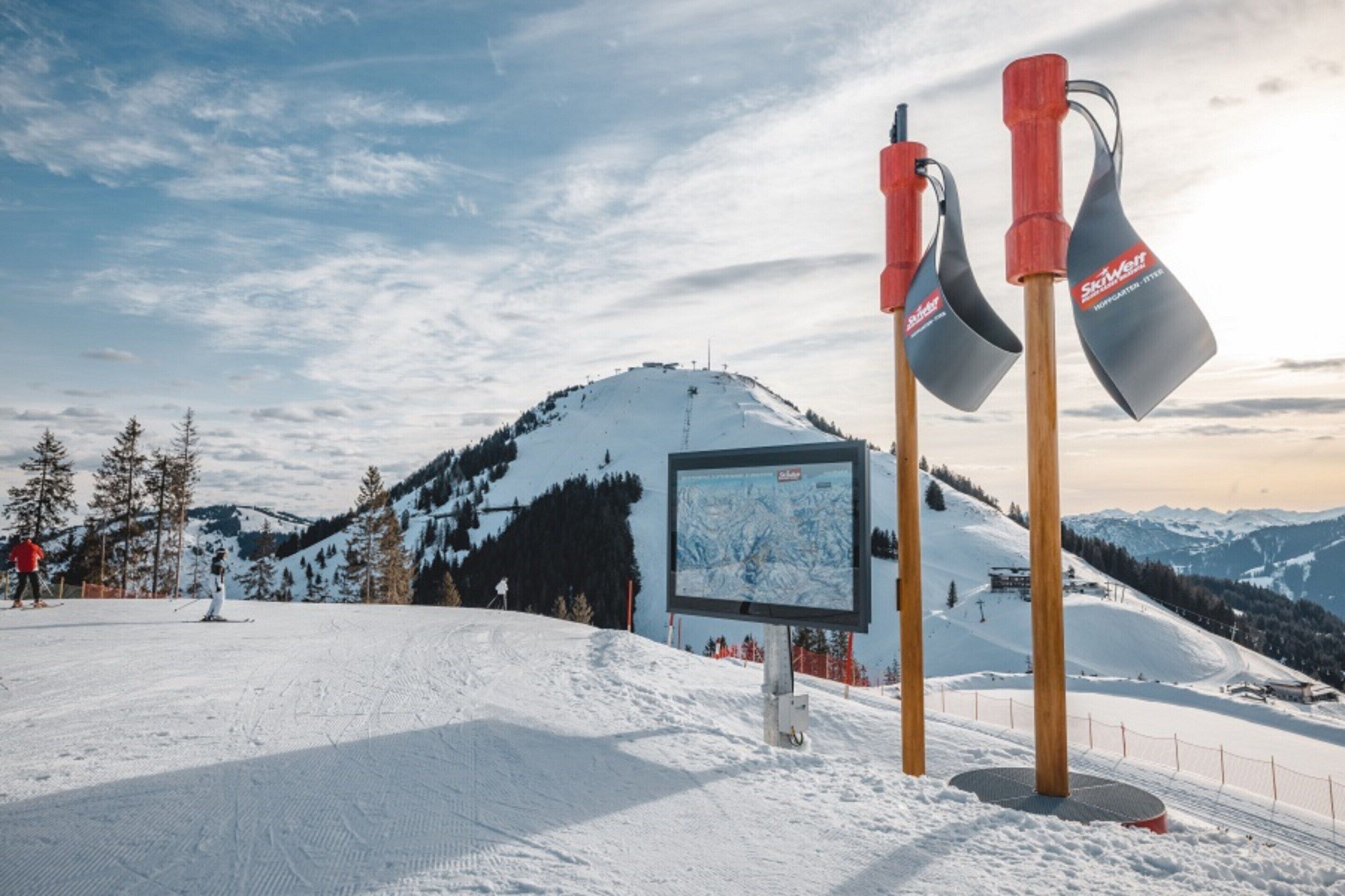 A ski resort with a snow-covered slope, a ski lift, and a signboard.