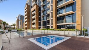 Ein modernes Wohngebäude mit einem Dachpool, umgeben von Grünflächen und blauem Himmel.