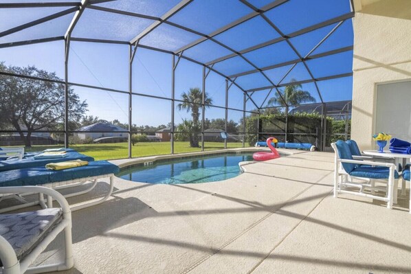 A covered outdoor pool area with lounge chairs and a flamingo float.