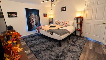 A bedroom with a bed, a chandelier, a wall with a poster, and a door.