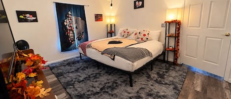 Ein Schlafzimmer mit einem Bett, einer Kristalllüster, einer Wand mit einem Poster und einer Tür.