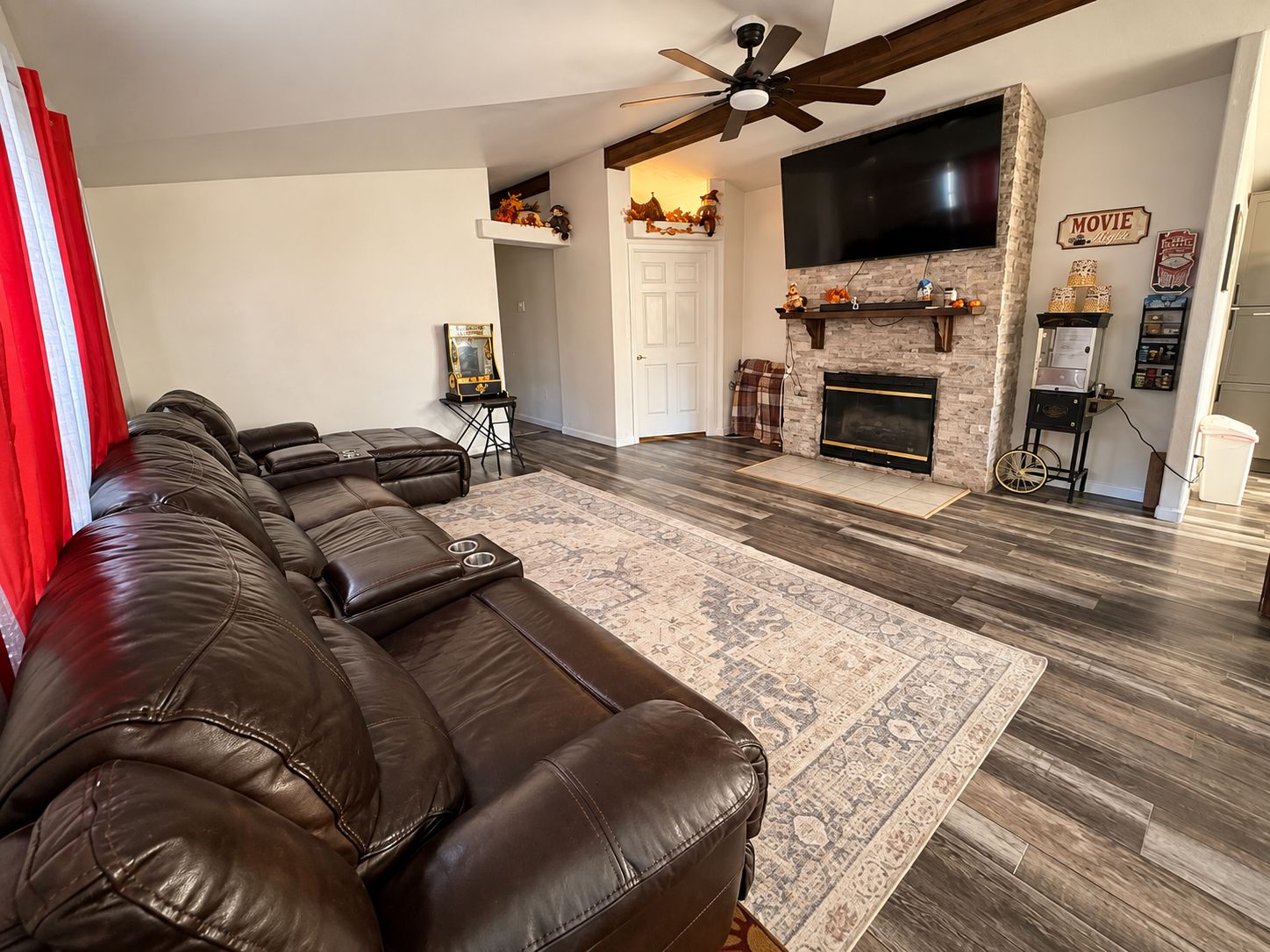 A living room with a sectional sofa, a fireplace, a television, and a ceiling fan.