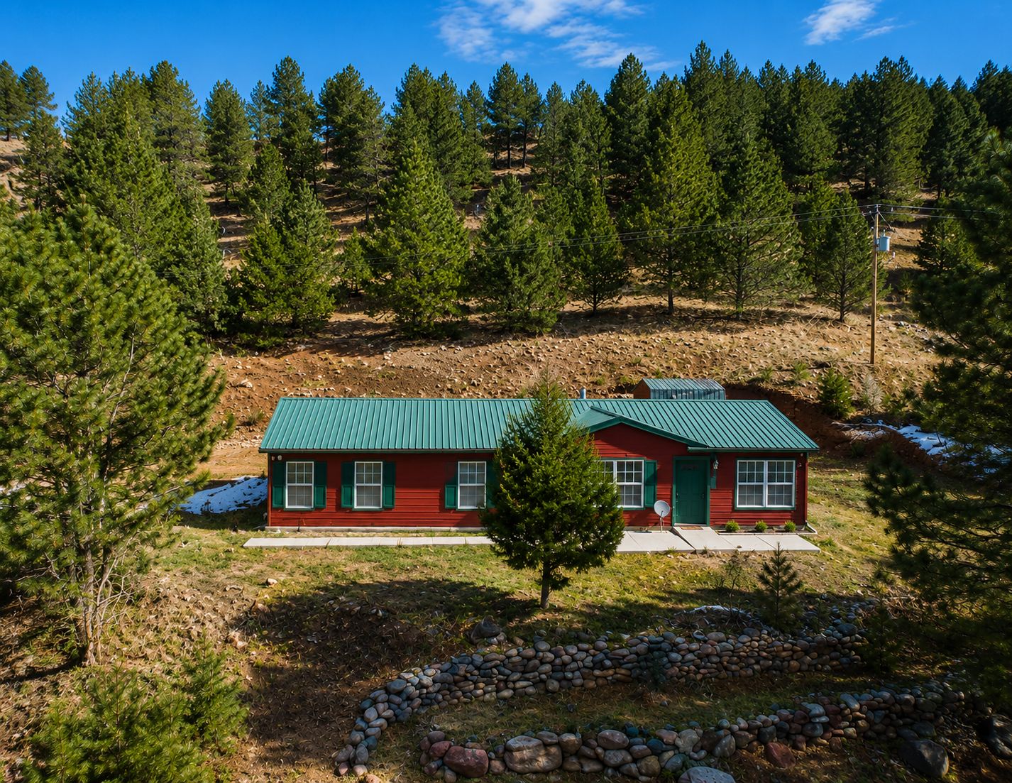 Eine rote Holzhütte mit einem grünen Dach, umgeben von einem Wald.