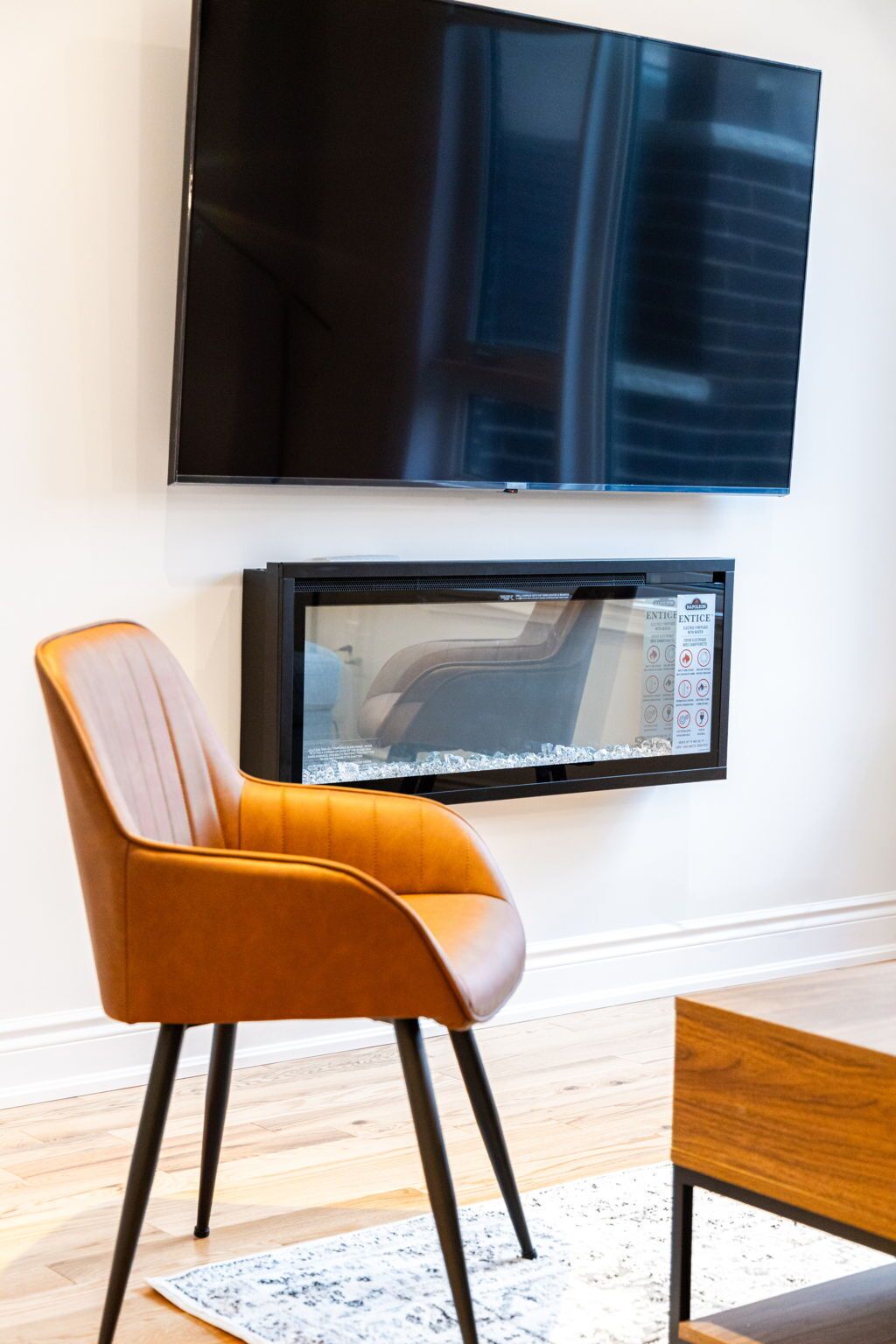 Ein modernes Wohnzimmer mit einem flachbildfernseher an der Wand, einem Ledersessel und einem Couchtisch aus Holz.