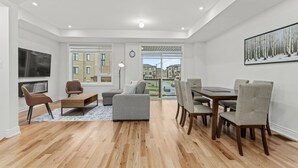 A modern living room with a sofa, armchairs, a coffee table, and a dining area with chairs and a table. - Modern Home With Parking Near Canada's Wonderland! (Vaughan)