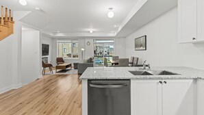 A modern kitchen with white cabinetry, a granite countertop, and a dishwasher. - Modern Home With Parking Near Canada's Wonderland! (Vaughan)