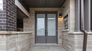 A double door entrance with a stone base and a brick wall. - Modern Home With Parking Near Canada's Wonderland! (Vaughan)