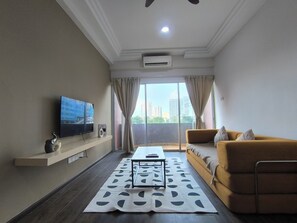 A modern living room with a sofa, a coffee table, a flat-screen TV, and a view of a cityscape through large windows. - MH Maison by Manhattan Group  (Kuala Lumpur)