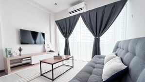 A modern living room with a grey sofa, a wooden coffee table, a flat-screen TV, and a bookshelf. - MH Maison by Manhattan Group  (Kuala Lumpur)
