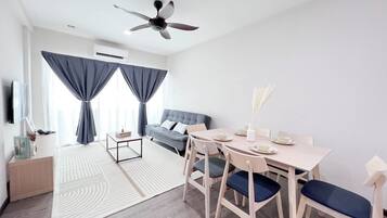 A modern living room with a sofa, dining table, and chairs. There is a ceiling fan and an air conditioning unit.