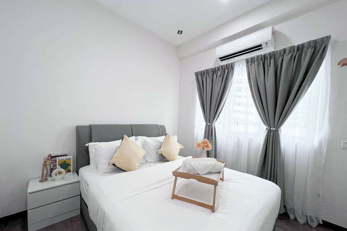 A modern bedroom with a grey headboard, white bedding, and grey curtains.