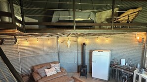 A cozy interior with a sofa, rug, kitchen area, and a rustic ceiling. - UNIQUE Grainbin Ranch Stay (Johnson City)