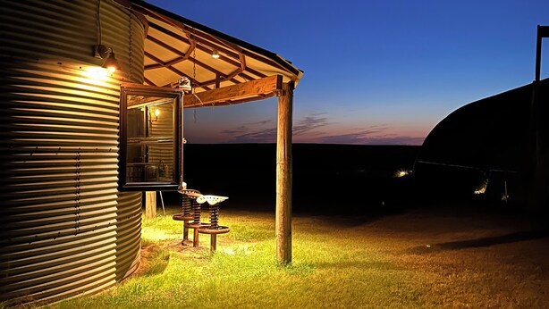 A rustic building with a covered patio area, a wooden table, and a metal structure. - UNIQUE Grainbin Ranch Stay (Johnson City)