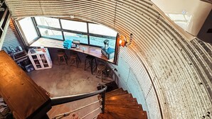 A spiral staircase in a building with a curved ceiling and a view of a bar area with stools and a counter. - UNIQUE Grainbin Ranch Stay (Johnson City)