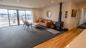 A modern living room with a sofa, coffee table, and a fireplace. - Tussock Bend Horizons (Twizel)