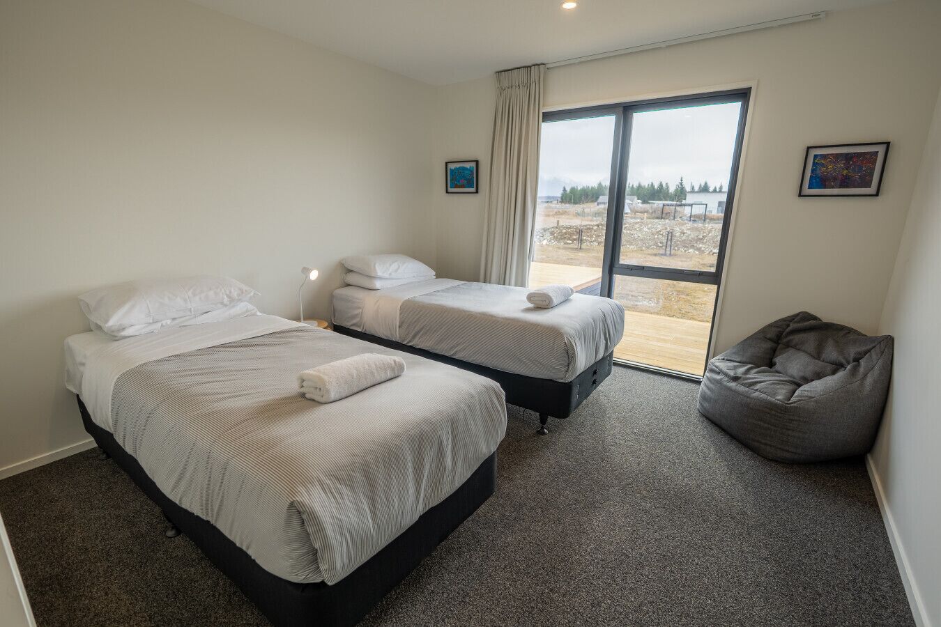 A hotel room with two beds, a large window, and a bean bag chair.