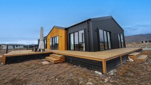 A modern house with a wooden deck, large windows, and a black exterior. - Tussock Bend Horizons (Twizel)