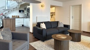 Ett modernt vardagsrum med en soffa, ett soffbord och en matplats med en trappa.