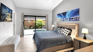 Une chambre moderne avec un grand lit, un ventilateur de plafond et des œuvres d’art accrochées aux murs.