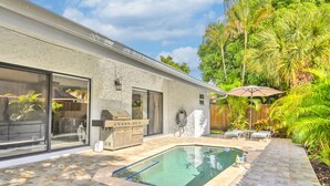 Une maison moderne dotée d’une piscine, d’un barbecue extérieur et de mobilier de jardin.