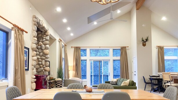 A spacious dining area with a wooden table, grey upholstered chairs, and a stone wall feature.