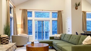 A living room with a green sofa, a round coffee table, and a stone fireplace.
