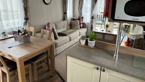 Un salon confortable avec un canapé, une table à manger et un coin cuisine équipé d’un four à micro-ondes.