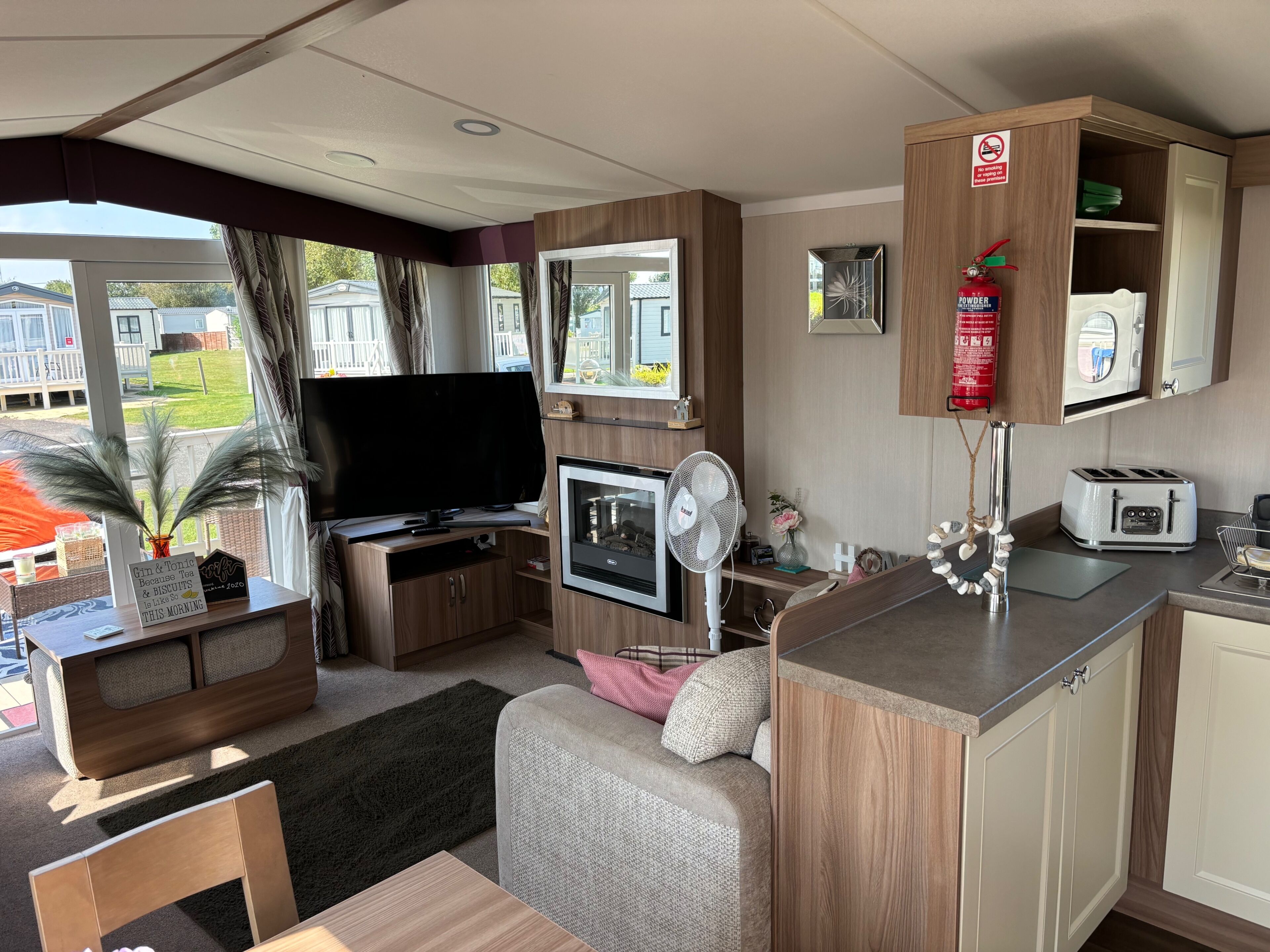 A compact living space with a television, kitchenette, and a view of the outdoors.
