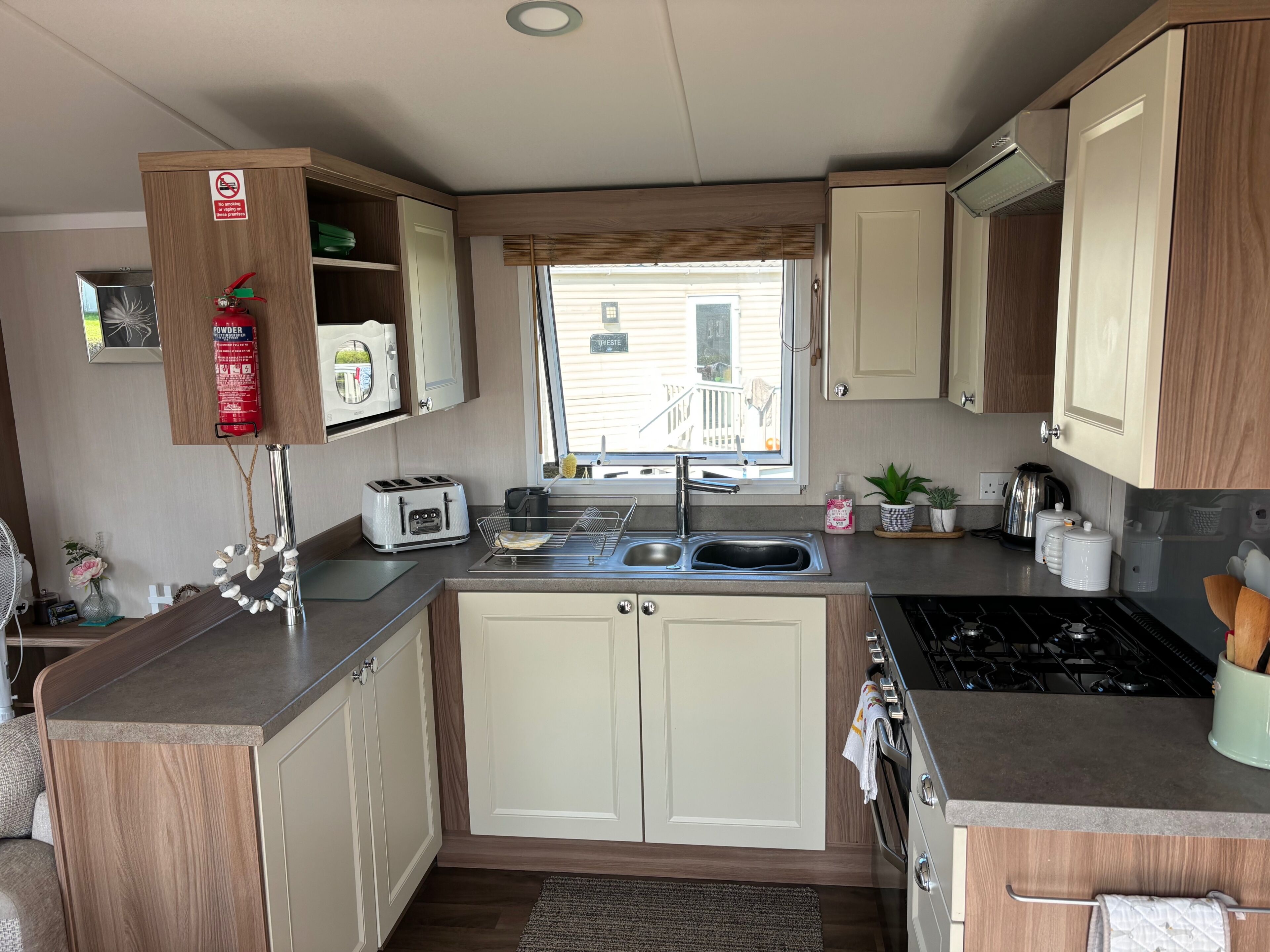 A compact kitchen with a built-in stove, a sink, and a window with a view of a house.