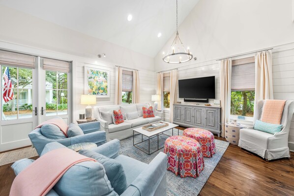 A spacious living room with a large TV, comfortable seating, and a view of the outdoors. - 5BR WaterColor Retreat: Beach Club Passes, Bikes, Electric Cart, Carriage House, Outdoor fireplace! (Santa Rosa Beach)