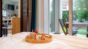 A hotel room with a bed, a breakfast tray with pastries, a coffee cup, and a red rose.
