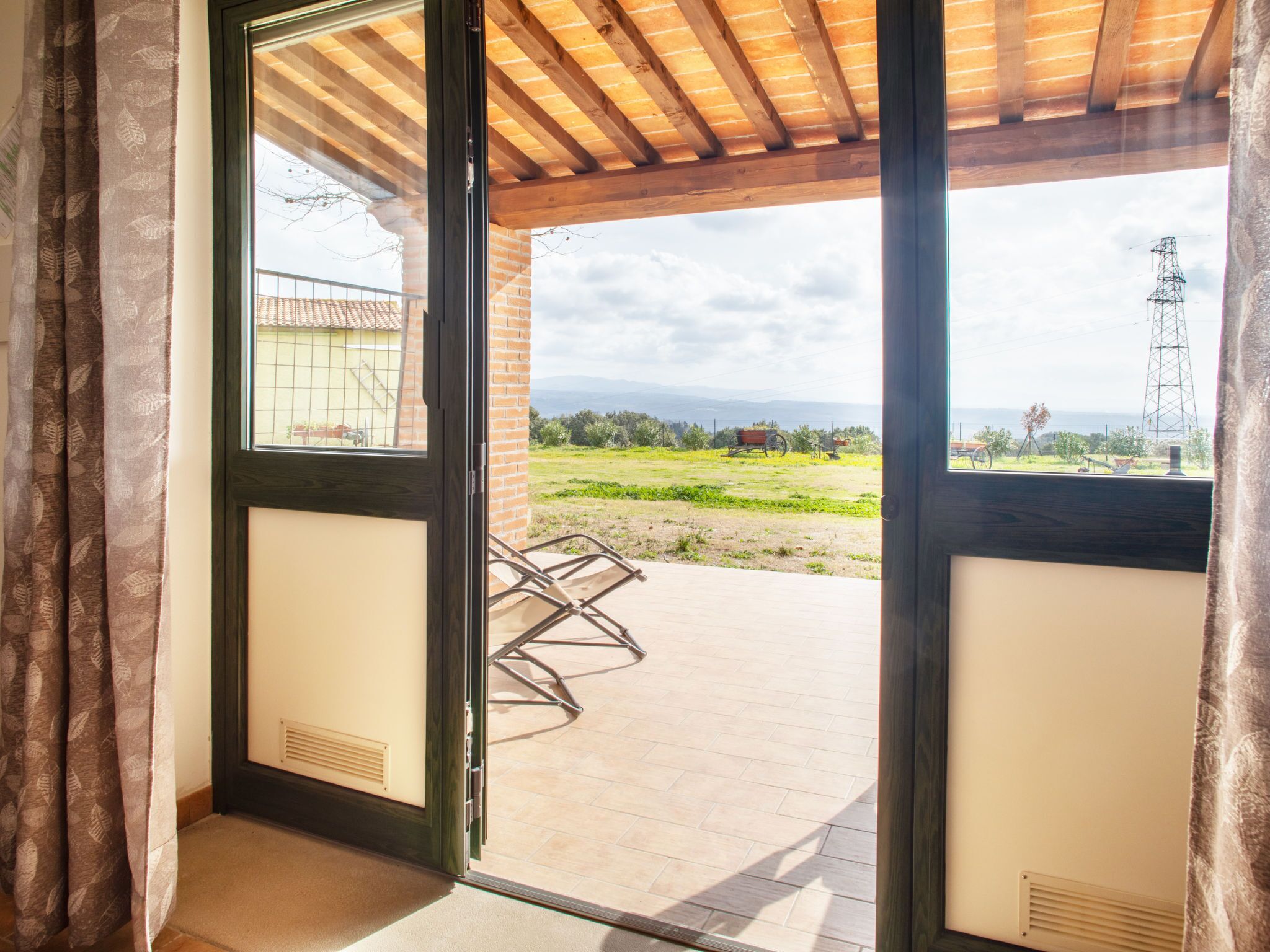 Une pièce dotée d’une porte-fenêtre coulissante donnant sur un patio extérieur avec une chaise en métal.